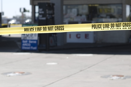 Police secure crime scene with yellow crime scene tape that surrounds the gas station